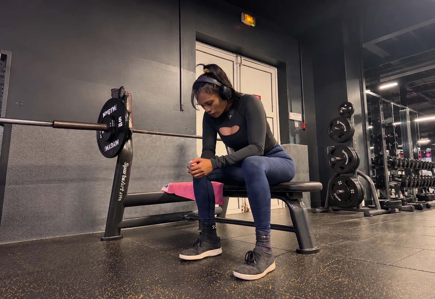 Nouria assise sur un banc de musculation, concentrée avant sa série